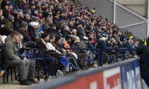 Disabled fans in wheelchairs watch from the stands of a football ground