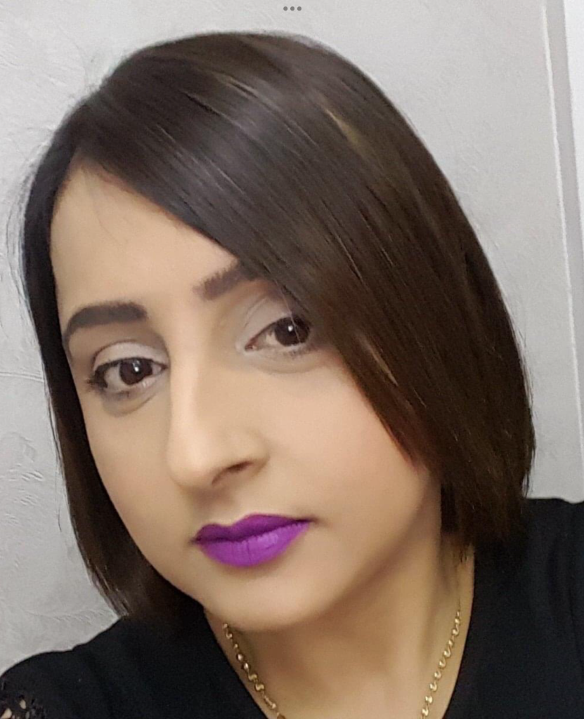 Headshot of Amarjit, who has a brown bob hairstyle and purple lipstick